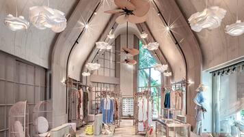 Una boutique espaciosa con techo alto, vigas de madera y un pasillo central que conduce a un gran ventanal.