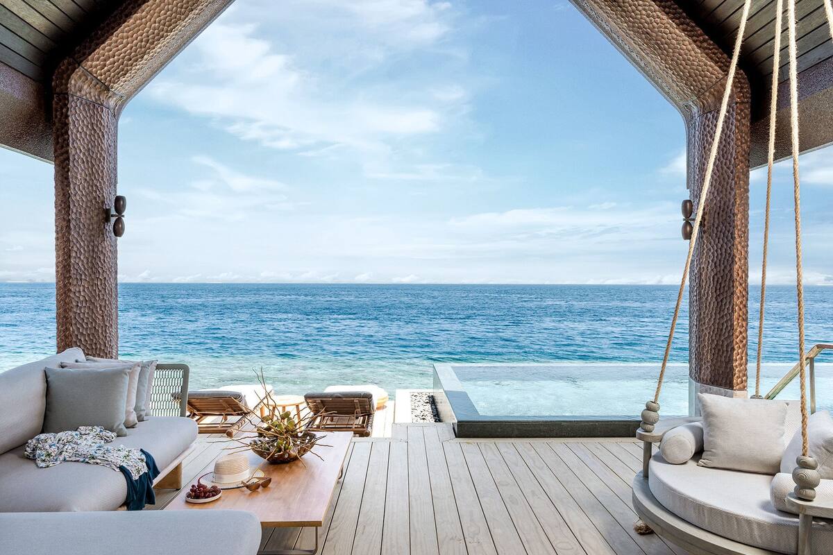 Una terraza con vista al océano, un sofá y una mesa con un florero y un pastel.