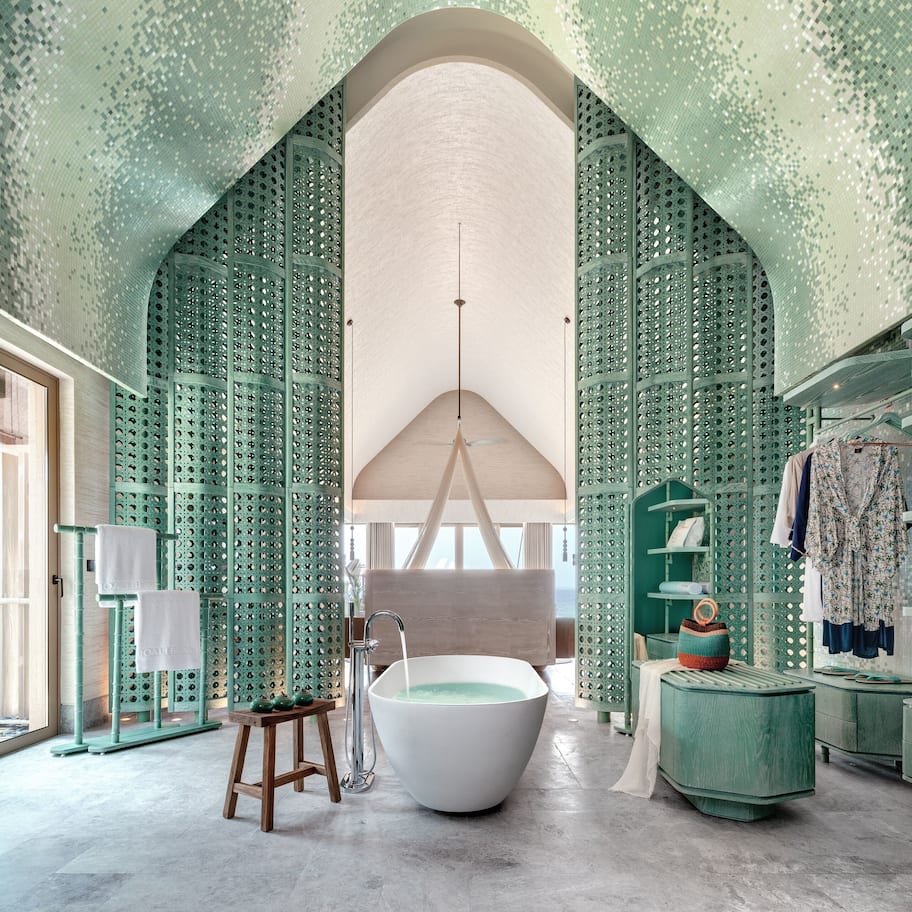 A bathroom with a freestanding bathtub, a wooden stool, and a green vanity.