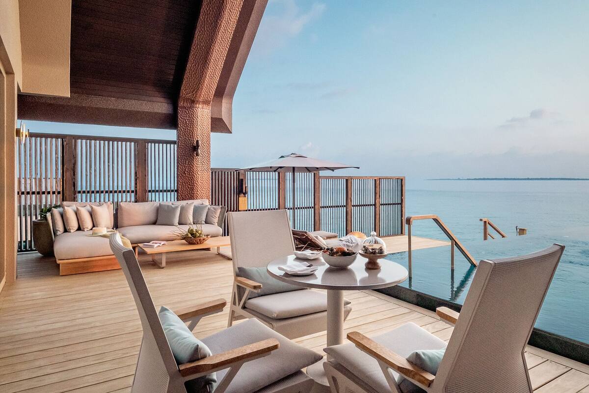 Terraza con sofá, sillas y una mesa con vista a una piscina.