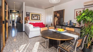 Un soggiorno moderno con un tavolo da pranzo rotondo, un divano rosso e un quadro grande appeso al muro.