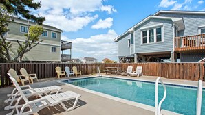 Une piscine avec des chaises longues et une terrasse en bois.