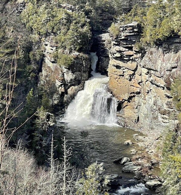 Une cascade entourée d’un paysage rocheux et d’une végétation clairsemée.