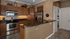 Una cocina con armarios de madera, electrodomésticos de acero inoxidable y encimera de granito.