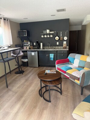 Un espacio habitable compacto con kitchenette, comedor y sofá.