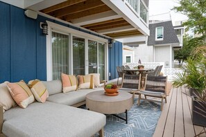A covered patio with a sofa, chairs, and a small table.