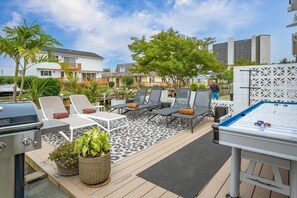 A deck with lounge chairs, a barbecue grill, and a foosball table.