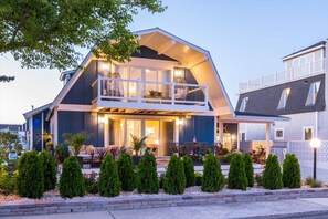 A modern two-story house with a balcony, large windows, and a well-maintained garden.