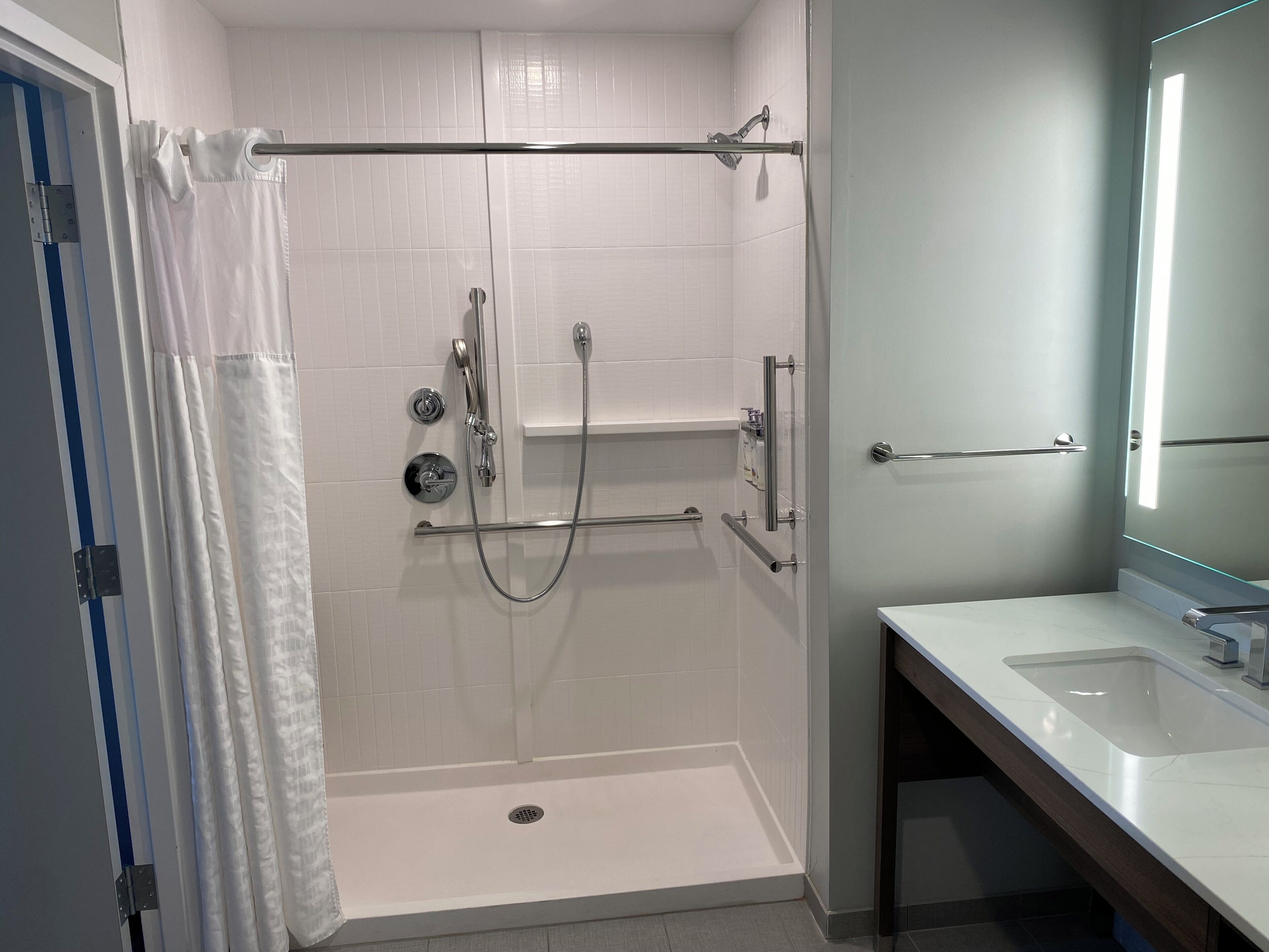 Un baño moderno con ducha a nivel de suelo, inodoro y lavamanos.