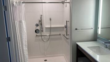 Un baño moderno con ducha a nivel de suelo, inodoro y lavamanos.