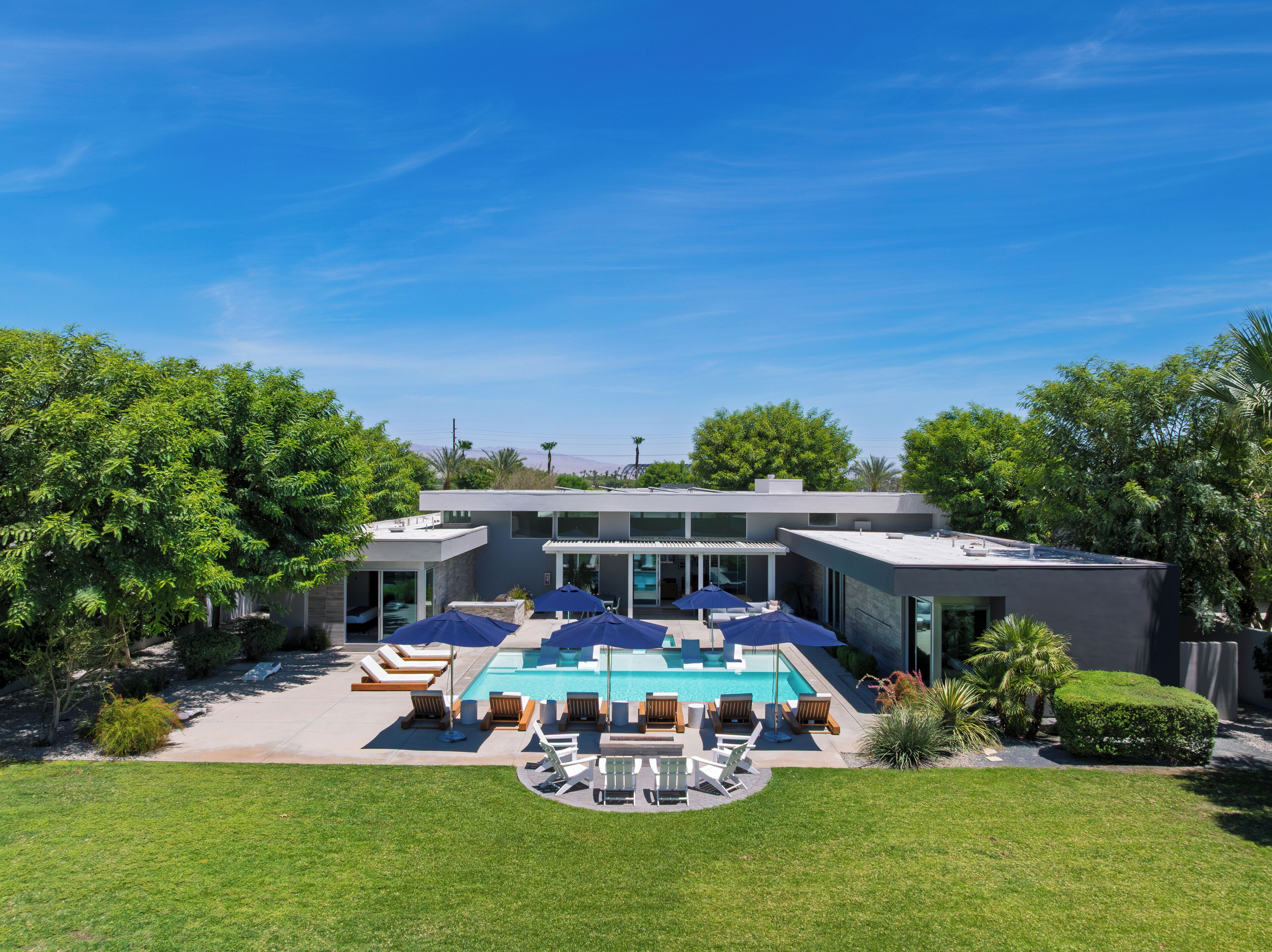 A modern house with a swimming pool, outdoor seating, and a well-maintained lawn.