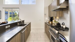 A modern kitchen with a large island, stainless steel appliances, and wooden cabinets.