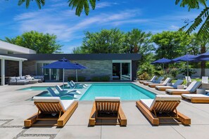 A modern outdoor pool area with lounge chairs and umbrellas.