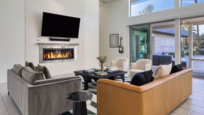 A modern living room with a fireplace, comfortable seating, and a large TV.
