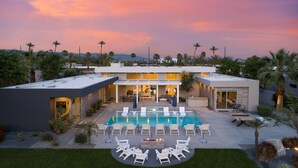A modern house with a swimming pool, outdoor seating, and a well-maintained lawn.