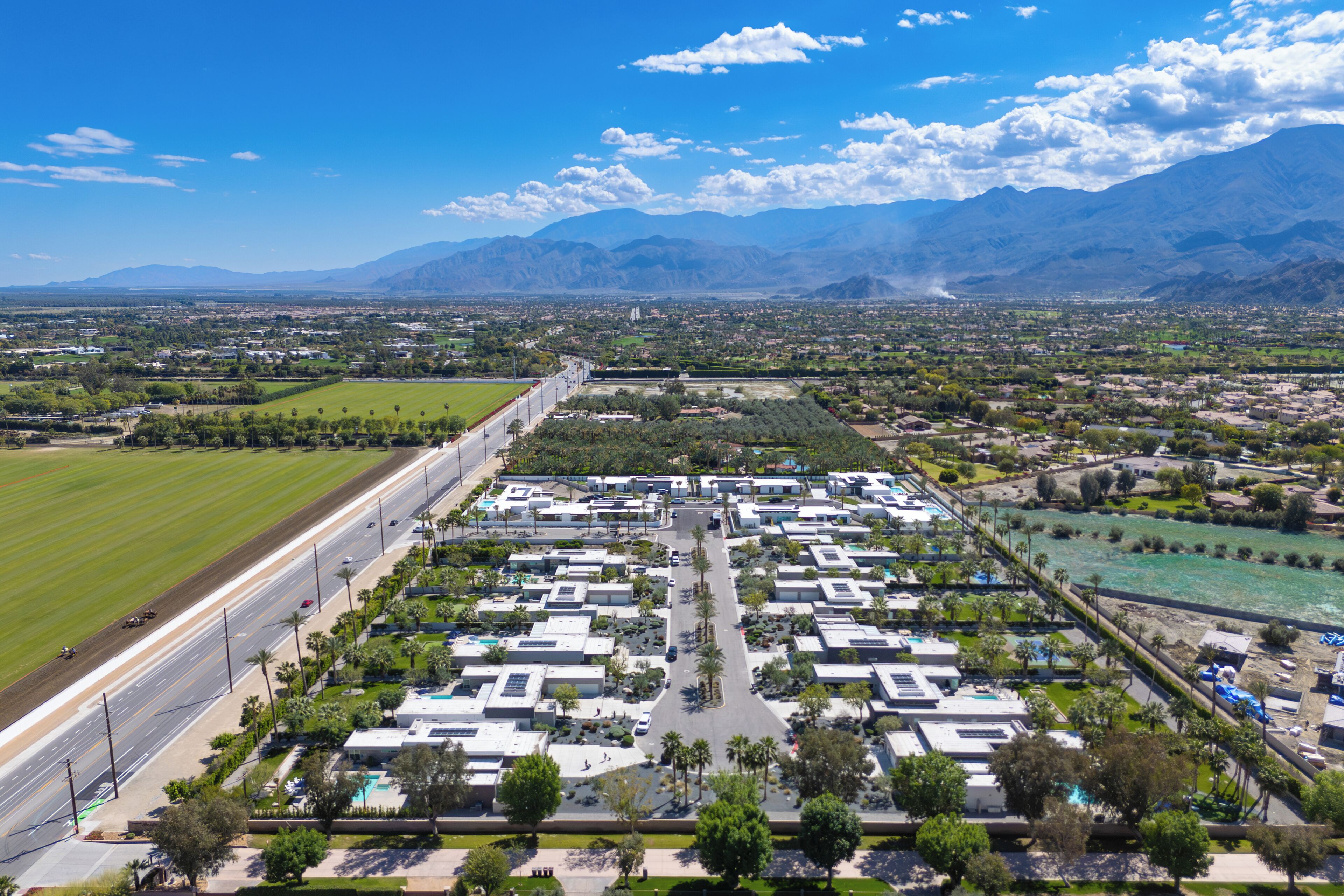An aerial view of a residential area with a large parking lot, a road, and a river.