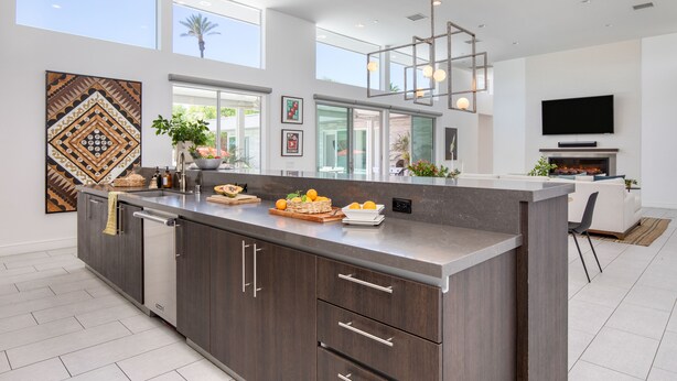 A modern kitchen with a large island, built-in appliances, and a dining area with a flat-screen TV and fireplace.