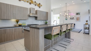 A modern kitchen with a central island, bar stools, and a decorative wall piece. - Private Pool + Spa + Pickleball Court + Fire Pit • Near La Quinta | Polo Villa 4 (La Quinta)