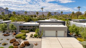 A modern building with a flat roof, surrounded by landscaped gardens and palm trees, with mountains in the background. - Private Pool + Spa + Pickleball Court + Fire Pit • Near La Quinta | Polo Villa 4 (La Quinta)