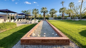 A courtyard with a shuffleboard table, lounge chairs, and palm trees. - Private Pool + Spa + Bocce Ball Court + Fire Pit • Near La Quinta | Polo Villa 5 (La Quinta)