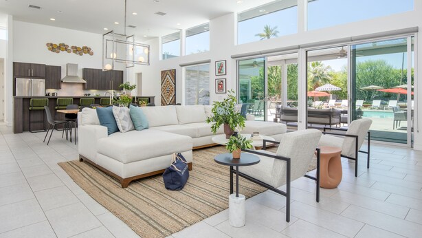 A spacious living area with a white sofa, a dining table, and a kitchen in the background. - Private Pool + Spa + Bocce Ball Court + Fire Pit • Near La Quinta | Polo Villa 5 (La Quinta)