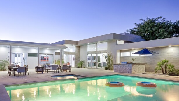 Une maison moderne dotée d’une piscine, de mobilier d’extérieur et d’un espace patio.