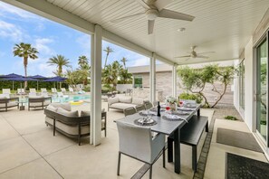 A covered outdoor area with a pool, lounge chairs, and a dining table set for two. - Sleeps 16 • Private Pool + Spa + Putting Green • Near La Quinta | Polo Villa 10 (La Quinta)
