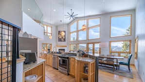 Una cocina amplia con ventanas grandes, un comedor y un techo alto con un lámpara en forma de estrella.