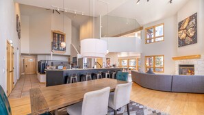Una cocina amplia con una isla grande, un comedor con mesa y sillas de madera, y un rincón de estar acogedor con chimenea.