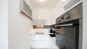 Eine moderne Küche mit weißen Schränken, einem eingebauten Backofen und einem Fenster über der Spüle.