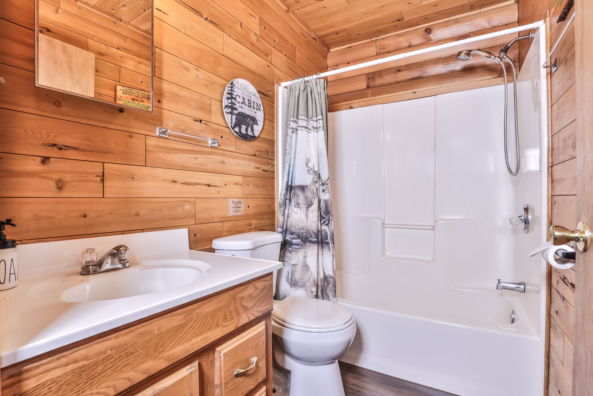 A wooden cabin bathroom with a sink, toilet, and shower.