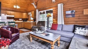 A cozy cabin interior with a wooden interior, a dining area, a sofa, and a fireplace.