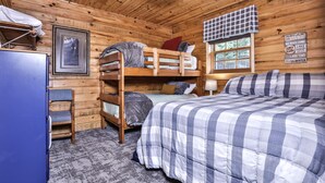 A cabin-style room with bunk beds, a desk, and a window with a view of trees. - Lakeside wilderness resort cabin with dock, fire pit, on-site store, bait shop! (Watersmeet)
