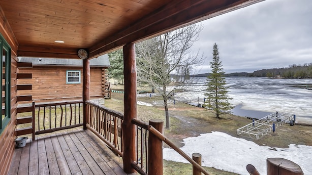 A wooden cabin with a porch overlooking a frozen river. - Lakeside wilderness resort cabin with dock, fire pit, on-site store, bait shop! (Watersmeet)