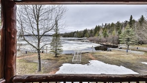 A view from a wooden cabin overlooking a frozen river with a wooden dock and a ladder leading into the water. - Lakeside wilderness resort cabin with dock, fire pit, on-site store, bait shop! (Watersmeet)