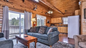 A cozy cabin interior with a sofa, coffee table, and a kitchen area. - Lakeside wilderness resort cabin with dock, fire pit, on-site store, bait shop! (Watersmeet)