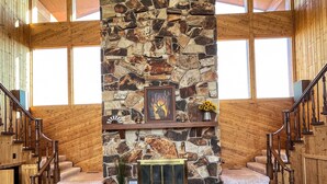 A spacious living area with a stone fireplace, leather sofas, and a wooden staircase. - Large cabin with amazing views, mountains, sunsets, and wildlife.
 (Pinedale)