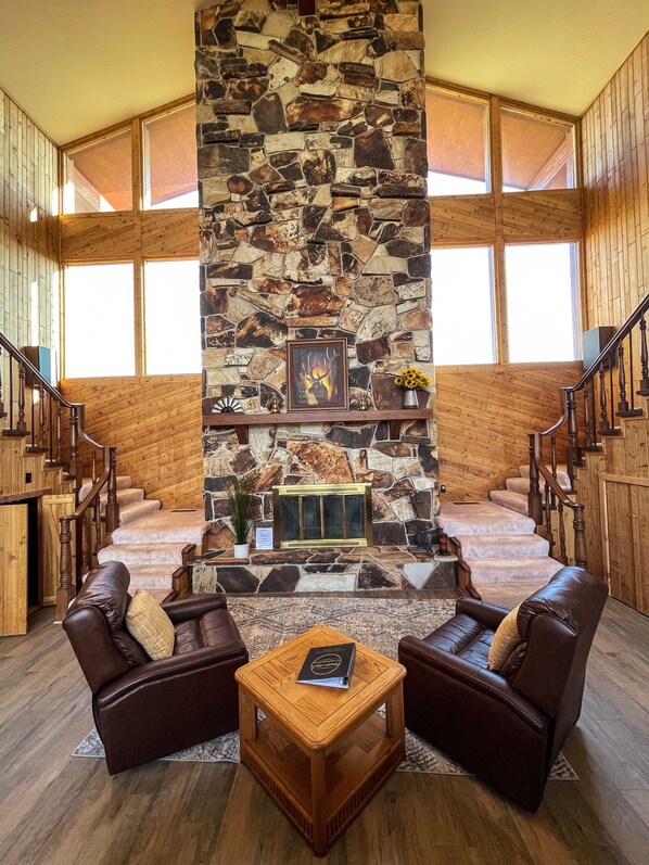 A spacious living area with a stone fireplace, leather sofas, and a wooden staircase. - Large cabin with amazing views, mountains, sunsets, and wildlife.
(Pinedale)