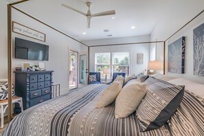 Une chambre à coucher avec un lit, une commode, un téléviseur et un ventilateur de plafond.