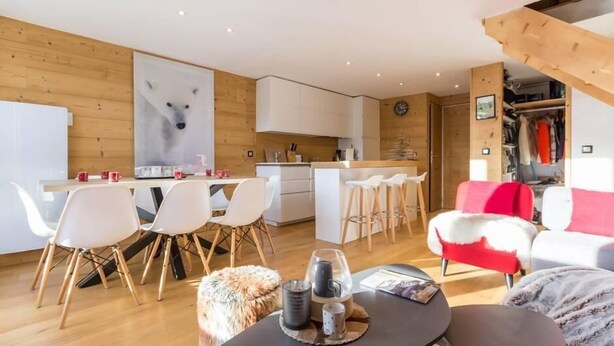 Un soggiorno moderno con angolo cottura, zona pranzo e posti a sedere.