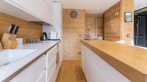 Una cucina moderna con mobili bianchi, piani di lavoro in legno e pannelli di parete in legno.