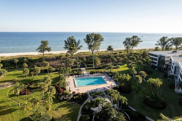 A resort with a swimming pool, palm trees, and a view of the ocean.