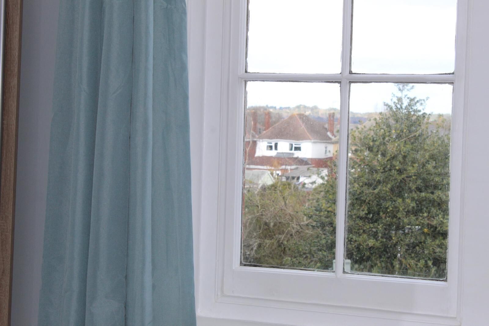 A window with a view of a house and trees.