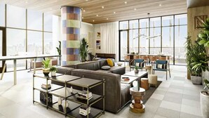 A modern living room with a sectional sofa, a coffee table, and a dining area with chairs. - Luxe Rainey St High Rise / Heated Pool / Gym / ATX (Austin)