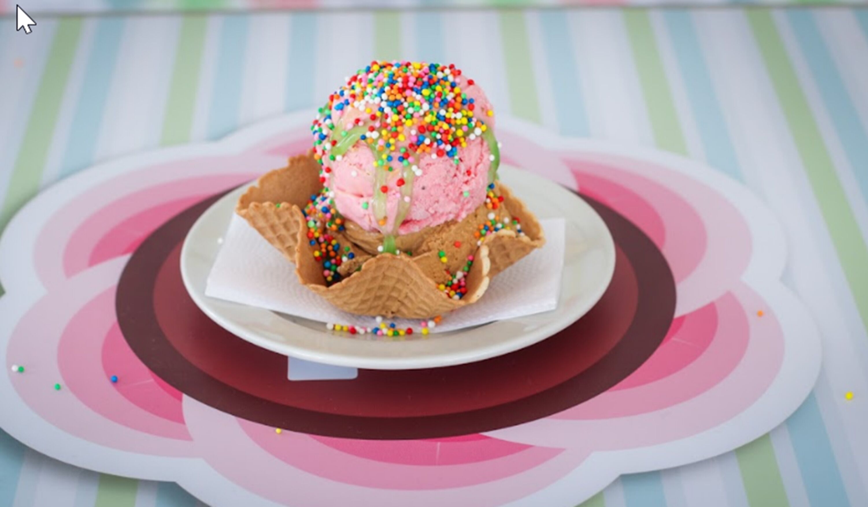 A dessert with ice cream and sprinkles on a plate with a striped background.