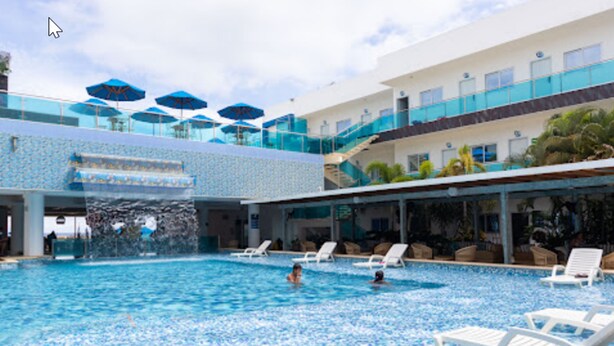A swimming pool with multiple levels, lounge chairs, and umbrellas. - Hotel Poblado Coveñas (Coveñas)