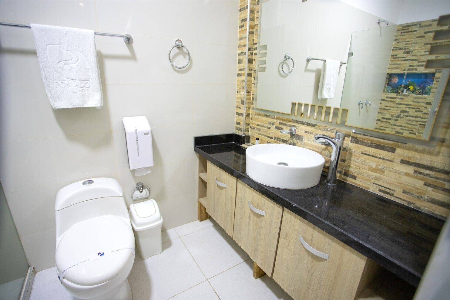A bathroom with a toilet, bidet, sink, and a mirror with a decorative backsplash.