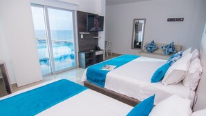 A hotel room with two beds, a TV, a desk, and a view of the ocean. - Hotel Poblado Coveñas (Coveñas)