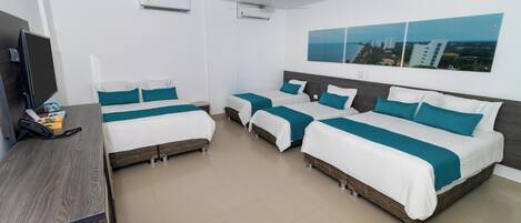 Een hotelkamer met drie bedden, een bureau, een televisie en een plafondventilator.