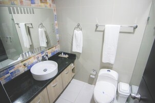 Un baño con lavamanos, espejo, inodoro y toallero.